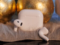 Apple Airpods 4 auf Teppichflor vor goldenen Kugeln