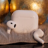 Apple Airpods 4 auf Teppichflor vor goldenen Kugeln
