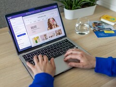 Hände tippen auf einem Laptop, auf dem Bildschirm ein Online-Shop.