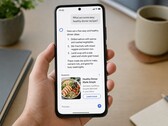 Hand hält ein Smartphone, auf dem unter einer KI-Antwort eine als gesponsert markierte Anzeige steht