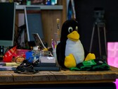 Plüschfigur des Linux-Pinguins Tux auf einem Werkstatttisch