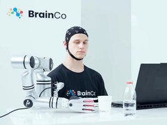 Ein Nutzer steuert mit BrainCos Technologie allein durch Gedanken eine Roboterhand, die einen Apfel greift