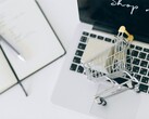 Miniatur-Einkaufswagen auf einer Laptop-Tastatur, auf dem Bildschirm steht Shop now