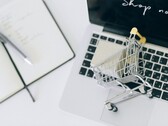 Miniatur-Einkaufswagen auf einer Laptop-Tastatur, auf dem Bildschirm steht Shop now