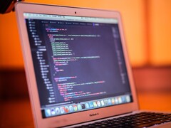 Aufgeklapptes MacBook zeigt Programmcode auf dem Bildschirm