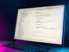 Laptop mit geöffnetem Code-Editor in einem dunklen Raum