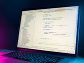 Laptop mit geöffnetem Code-Editor in einem dunklen Raum