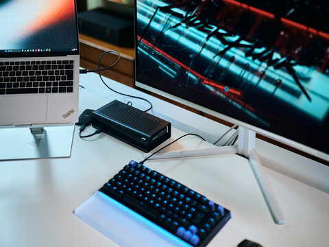 Lenovo ThinkPad X9 14 Laptop angeschlossen an die Aorus RTX 5060 Ti AI Box eGPU und einen Evnia Monitor mit Cyberpunk 2077 auf dem Schreibtisch.