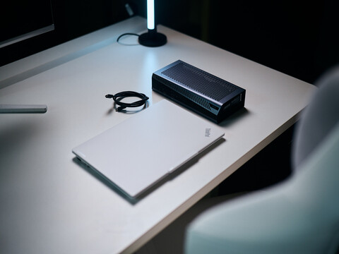Ein geschlossener weißer Lenovo ThinkPad Laptop liegt neben einer schwarzen Aorus RTX 5060 Ti AI Box eGPU und einem eingerollten Thunderbolt-Kabel auf einem hellen Schreibtisch.