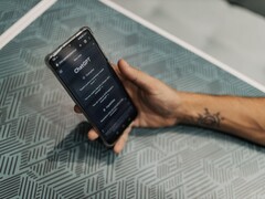 Hand hält ein Smartphone mit geöffneter ChatGPT-App über einem gemusterten Tisch