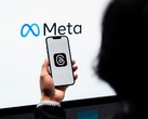 Hand hält ein Smartphone vor einem großen Meta-Logo