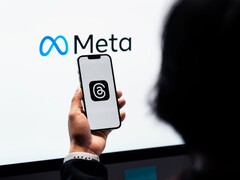 Hand hält ein Smartphone vor einem großen Meta-Logo