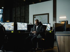 Sicherheitsanalyst in einem Kontrollraum vor mehreren Monitoren