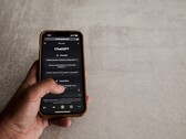 Hand hält ein Smartphone mit geöffneter ChatGPT-Oberfläche über einer grauen Steinfläche