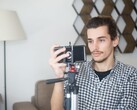 Junger Mann filmt sich zu Hause mit einem Smartphone auf einem Stativ
