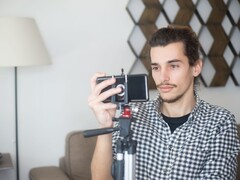 Junger Mann filmt sich zu Hause mit einem Smartphone auf einem Stativ