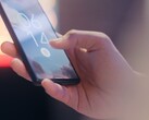 Hand hält ein Smartphone und entsperrt es per Fingerabdrucksensor auf dem Sperrbildschirm.