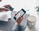 Person tippt auf einem Smartphone und hält in der anderen Hand eine Bankkarte