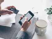Person tippt auf einem Smartphone und hält in der anderen Hand eine Bankkarte