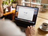 Person an einem Laptop mit geöffneter Google-Startseite, daneben eine Tasse Kaffee