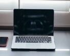 Aufgeklappter Laptop und Smartphone nebeneinander auf einem Schreibtisch bei Tageslicht
