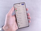 Hand hält ein Smartphone, auf dem Display läuft eine Update-Liste.