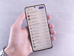 Hand hält ein Smartphone, auf dem Display läuft eine Update-Liste.