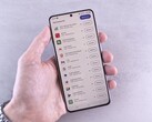 Hand hält ein Smartphone, auf dem Display läuft eine Update-Liste.