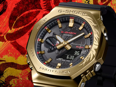 Die Casio G-Shock GBM-2100CX-9AJR mit gravierter goldfarbener Lünette, abgebildet vor einem stilisierten roten Hintergrund. (Bildquelle: Casio)