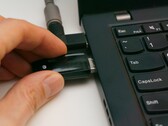 Hand steckt einen USB-Sicherheitsschlüssel in einen Laptop