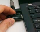 Hand steckt einen USB-Sicherheitsschlüssel in einen Laptop