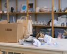 Pappkarton und Papiertüten auf einem Holztisch in einem Büro mit Regalen