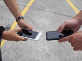Zwei Personen halten bei einer Übergabe zwei Smartphones nebeneinander