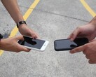 Zwei Personen halten bei einer Übergabe zwei Smartphones nebeneinander