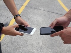 Zwei Personen halten bei einer Übergabe zwei Smartphones nebeneinander