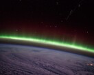 Ein von der ISS aufgenommenes Foto zeigt einen grünen Polarlichtbogen über den Wolken.