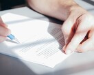 Eine Hand unterschreibt ein Dokument mit einem blauen Kugelschreiber