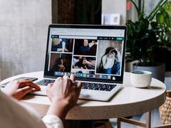 Person tippt an einem Laptop im Café, auf dem Bildschirm ein Browserfenster mit Tableiste und Adresszeile