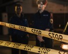 Zwei Polizisten stehen nachts hinter einem Absperrband mit der Aufschrift Stop