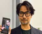 Hideo Kojima zeigt ein Poster zu Physint auf seinem Smartphone