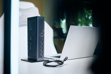 Rückansicht der vertikal aufgestellten Aorus RTX 5060 Ti AI Box eGPU mit sichtbar integrierten Anschlüssen neben einem weißen ThinkPad Laptop.
