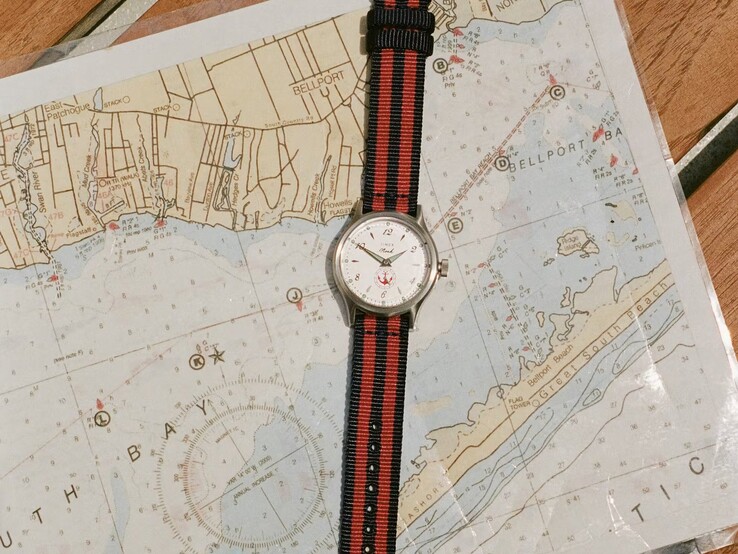 Noah x Timex MK1 Anchor mit marineblau-rot gestreiftem Textilarmband, die auf einer Seekarte liegt