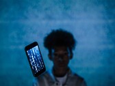 Schwebendes Smartphone mit Code auf dem Display vor blauem Hintergrund, dahinter eine unscharfe Person