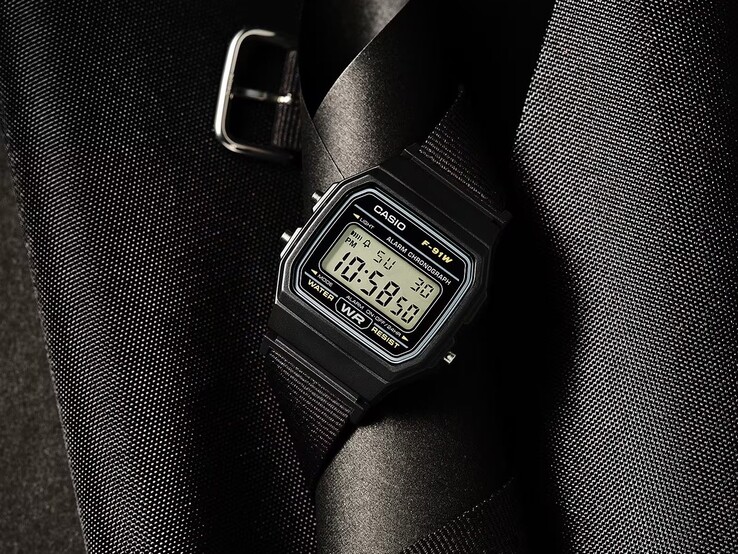 Digitale Armbanduhr Casio F-91WF-1A mit schwarzem Gehäuse, schwarzem Textilarmband und silberfarbenen Akzenten vor einem dunklen, strukturierten Hintergrund