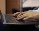 Hände tippen auf der Tastatur eines dunklen Notebooks