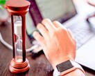 Sanduhr neben einer Hand auf einer Laptoptastatur