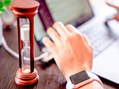 Sanduhr neben einer Hand auf einer Laptoptastatur