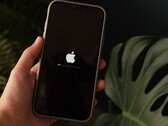 Hand hält ein iPhone, auf dem Display leuchtet das Apple-Logo mit Ladebalken.