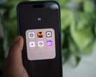 Hand hält ein Smartphone mit einem App-Ordner namens AI, darin unter anderem Gemini, ChatGPT und Claude