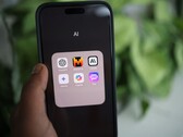 Hand hält ein Smartphone mit einem App-Ordner namens AI, darin unter anderem Gemini, ChatGPT und Claude